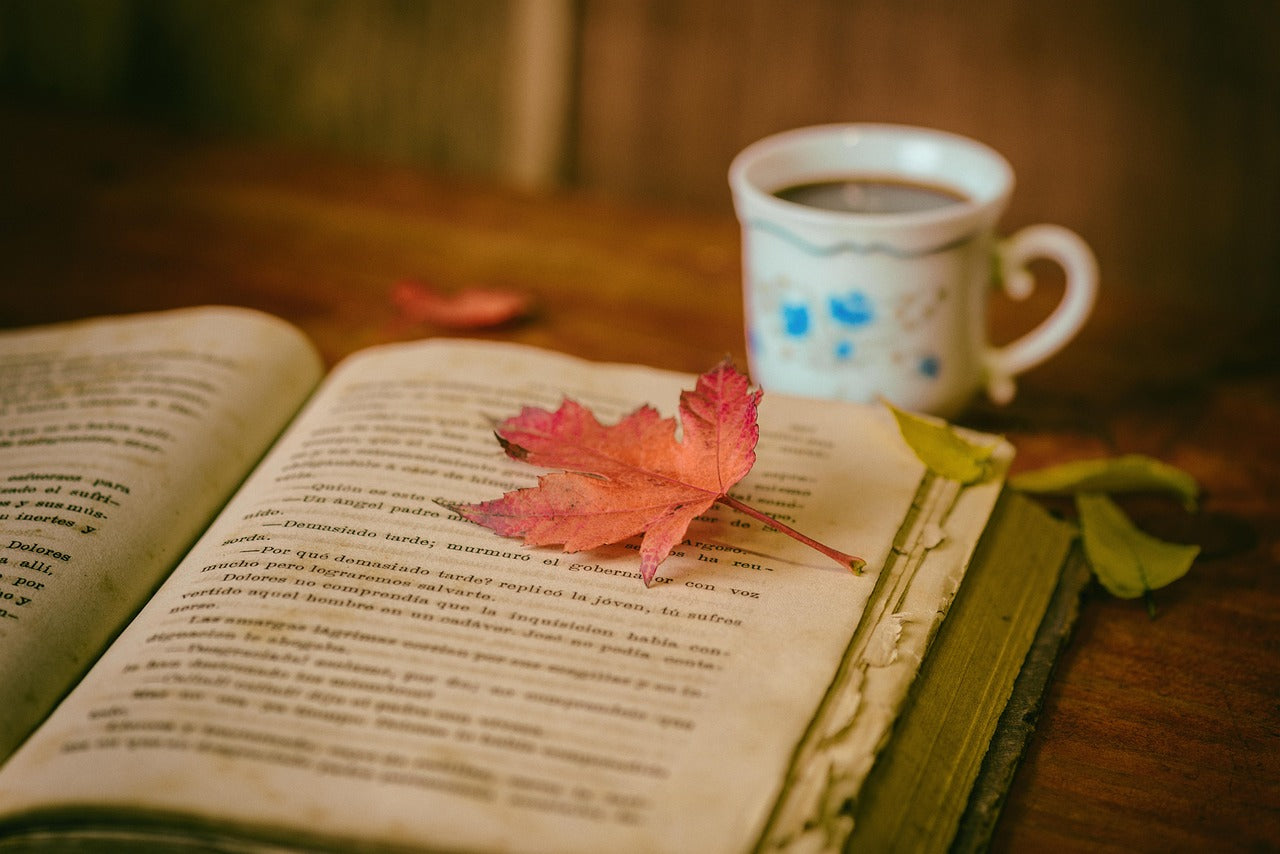 Regalos para amantes de la lectura: libro abierto junto a una taza de cafe